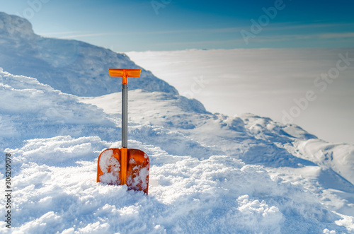 Fotografering Оrange avalanche shovel in powder fresh snow and place for writing text