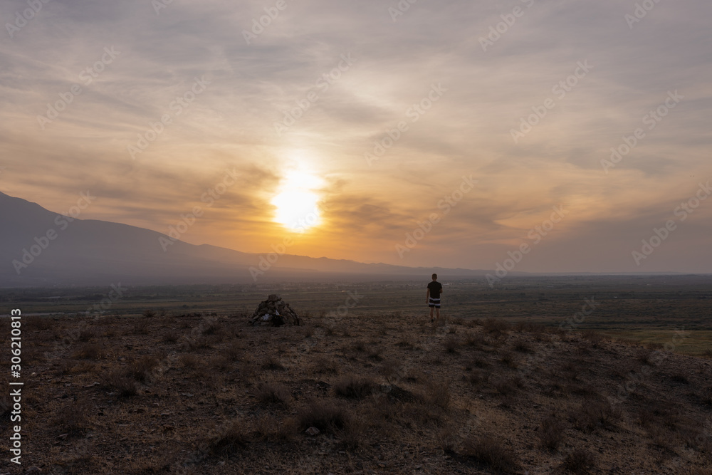 a man travels in Armenia, Yerevan. At sunset, she jumps silhouettes against the backdrop of Mount Ararat. Very beautiful landscape.