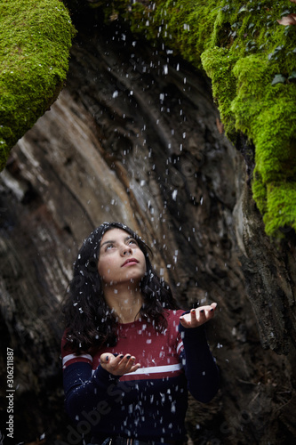 Young girl in the forest while snow falling.