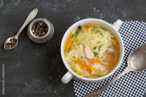 chicken soup with vegetables and noodles. on a dark background, close-up