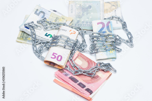 Dinero y cadenas, billetes de dinero rodeados de cadenas, metáfora de la vida en la que vivimos, encadenados o esclavos del dinero photo