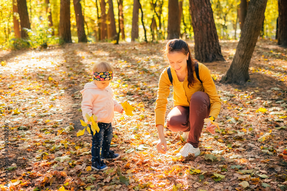 Little girl with mother knee and playing in autumn forest Little girl with mother knee and playing in autumn forest