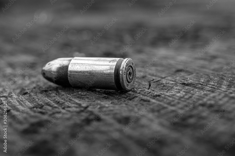close up of black and white bullet on wooden background close up of black and white bullet on wooden background