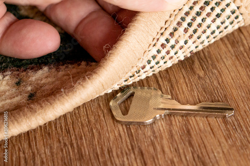 A man raises a key hidden under a mat