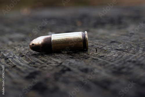close up of 9 mm caliber bullet on wooden background. Side view.