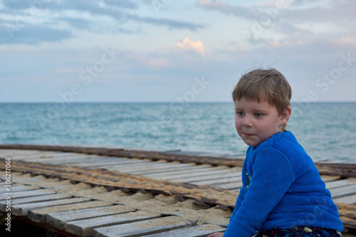 Quadro su tela boy with a surprised expression in the evening near the sea