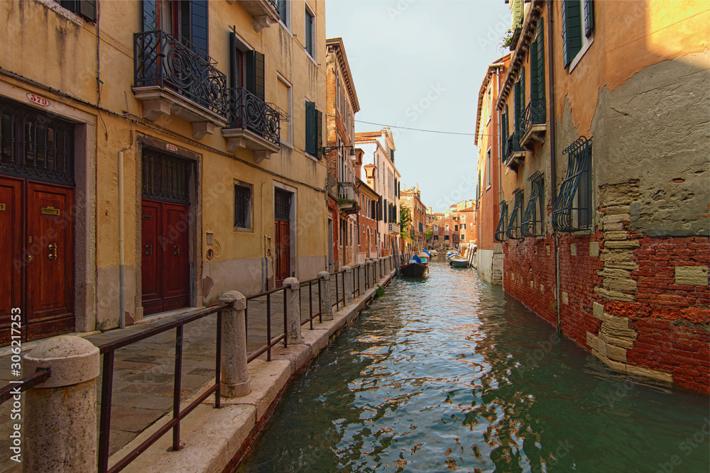 Stunning landscape view of street in Venice. Typical street with ancient building, narrow canal with turquoise water. Beautiful cobblestone pathway along the buildings. Venice, Italy
