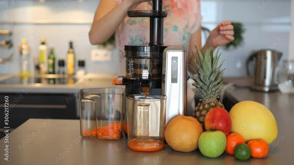 Woman making fruit juice using juicer machine in home kitchen, healthy eating lifestyle concept, slow motion video Woman making fruit juice using juicer machine in home kitchen, healthy eating lifestyle concept, slow motion video