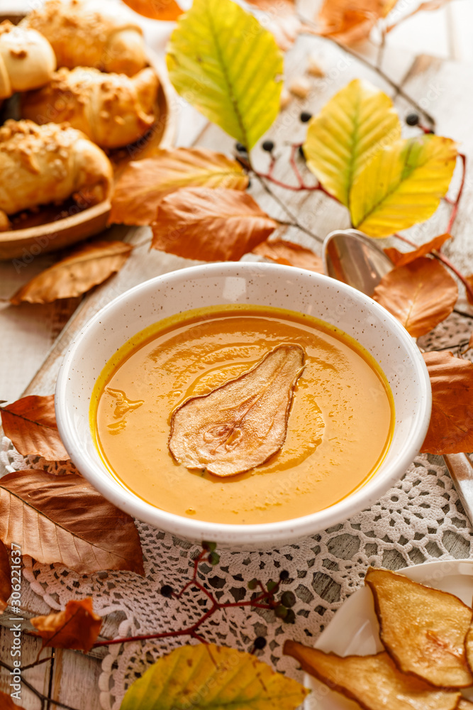 Pumpkin soup with the addition of pear chips in a white ceramic bowl. Delicious and healthy vegan soup Pumpkin soup with the addition of pear chips in a white ceramic bowl. Delicious and healthy vegan soup