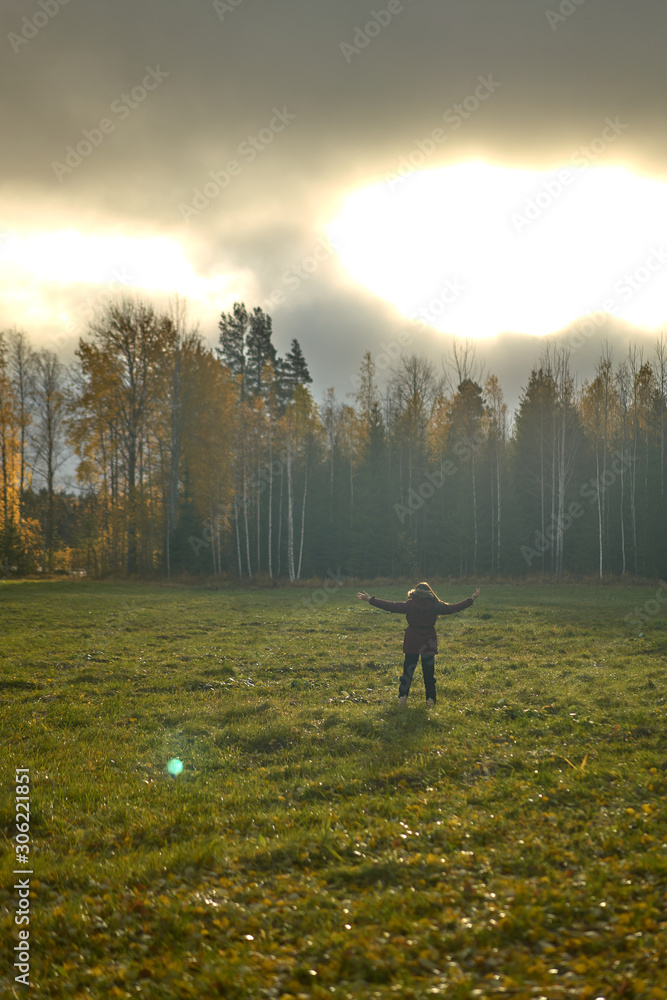 Person with open arms in the middle of a field surrounded by forest.incredible misty sky