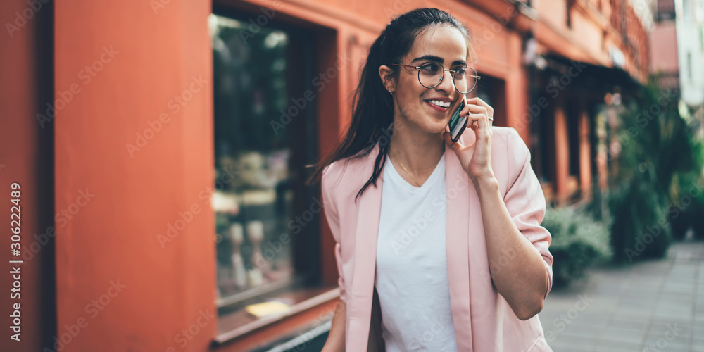 Happy Georgian female traveller enjoying smartphone conversation with friend during holidays time for visit historic center, positive woman in optical eyewear calling via mobile network app