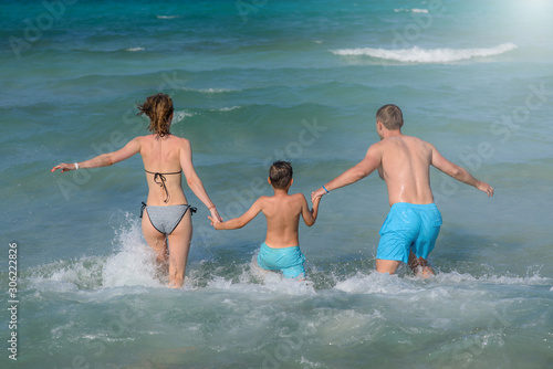 Happy European family is spending holidays on the seaside. They running to the sea smiling and holding hands. © Artem
