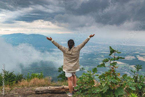 Tourist woman,standing on the top of the mountain admires the beauty of the landscape and rainy weather.View of the city of Annemasse and Geneva,Haute-Savoie in France.