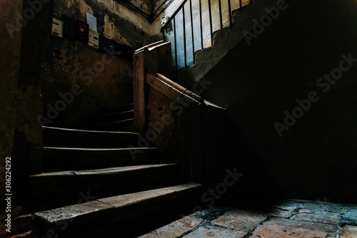 Old stone stairs in the dark atrium of a disused building in the old part of Bari, Italy.