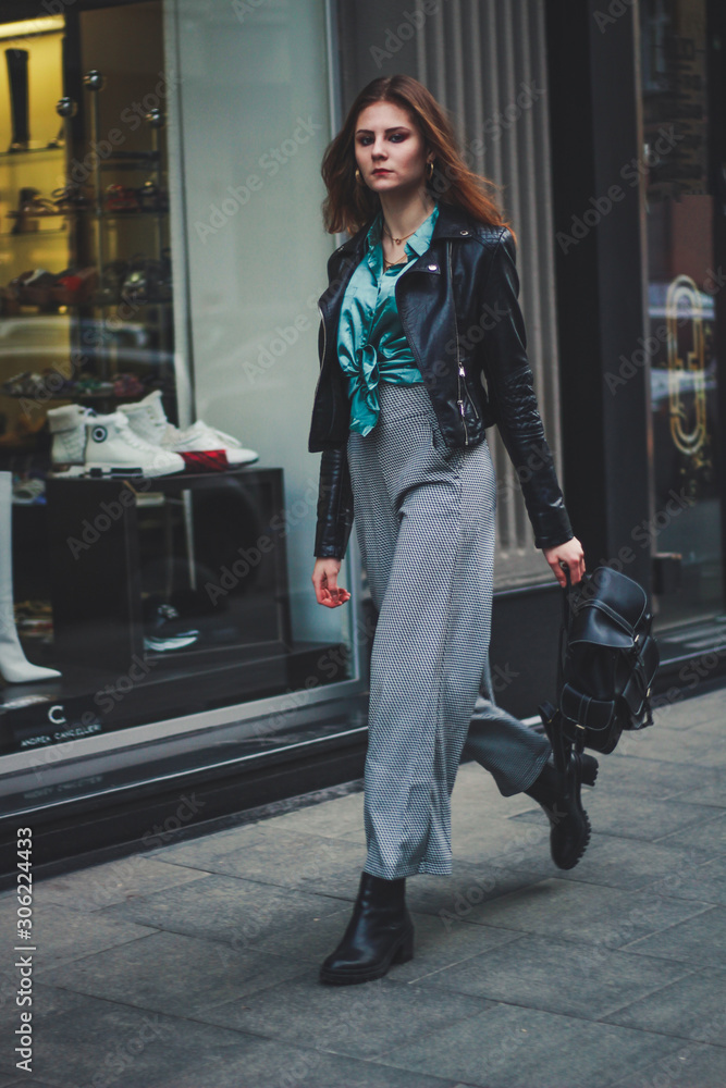 Fashion shooting. Wide trousers tube. Satin emerald blouse. Fashion trend.  Tall brunette model. Black eco leather jacket.Stylish backpack made of eco  leather. Handbag. Stock Photo | Adobe Stock