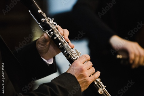 Clarinet player holding a metal transverse flute in his hands.