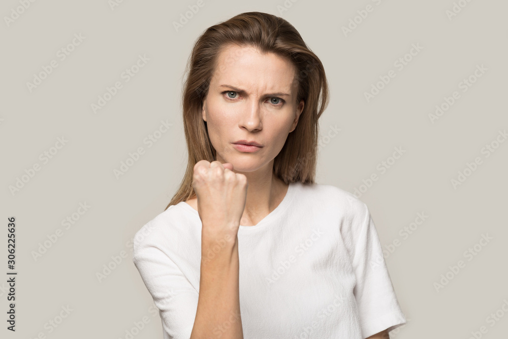 Angry young woman showing clenched fist at camera, warning Angry young woman showing clenched fist at camera, warning