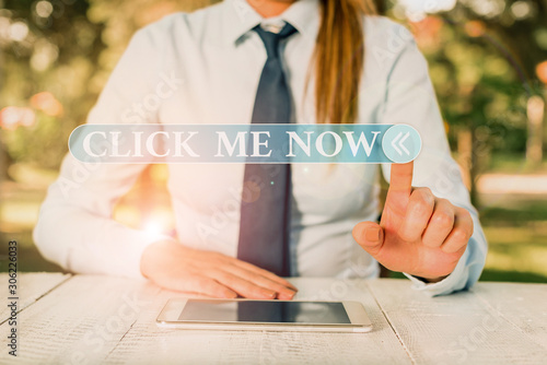 Handwriting text Click Me Now. Conceptual photo Internet helping desk Press the button Online Icon Nertwork Female business person sitting by table and holding mobile phone photo