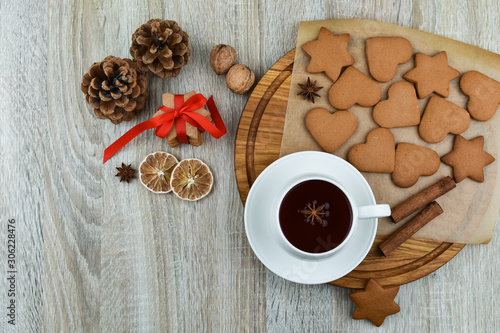 White cup of tea with cookies on a wooden table. Ginger, star anise, cones, lemon. Zero waste concept. New Year.