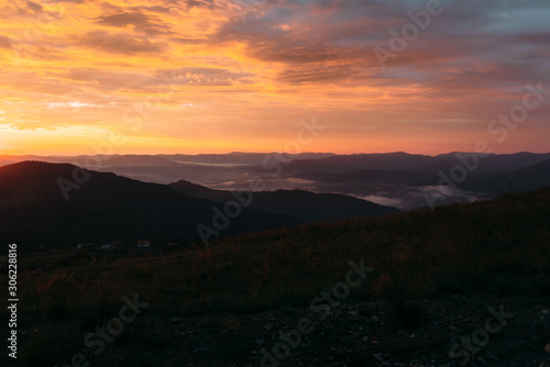 Bright red sunset over the mountains, fog over the terrain