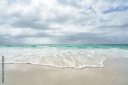 Smooth wave rolling onto a white sand beach