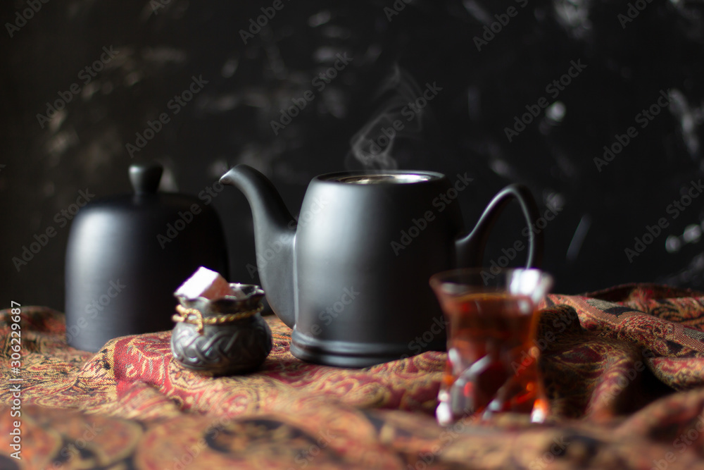 Black teapot, sweets and traditional tea glass armudu on scarf Black teapot, sweets and traditional tea glass armudu on scarf