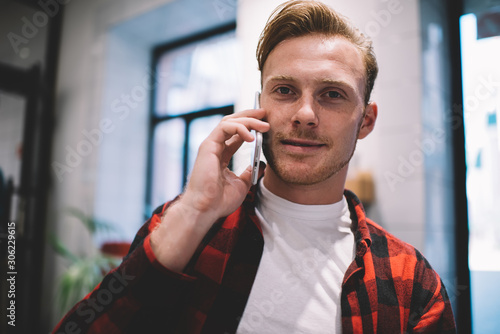 Confident guy speaking on smartphone in cafe