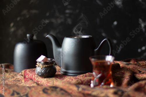 Black teapot  sweets and traditional tea glass armudu on scarf