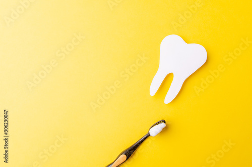 Paper tooth and toothbrush on a yellow background. From abve. Copy space photo