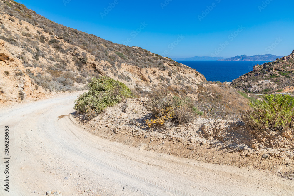 Dirty road with ocean and mountains in background