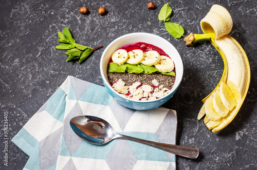 Healthy breakfast bowl - blueberry smoothie with banana, raspberry, almonds and chia seeds.