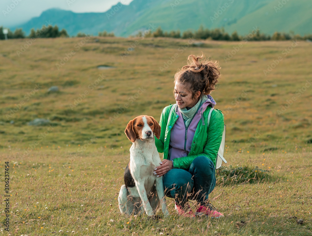 Smiling woman hugging her pet dog near face. Dog with a woman walking mountains outdoors . love and care for the pet.