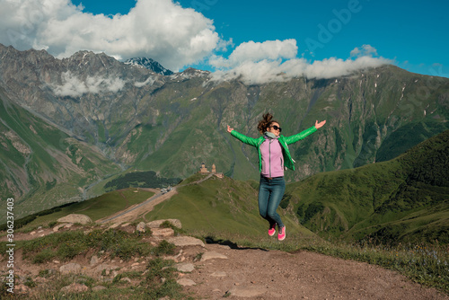 Curly woman happy jumping on peak mountains.Young woman outdoors. Freedom concept. 