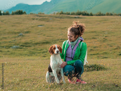 Smiling woman hugging her pet dog near face. Dog with a woman walking mountains outdoors . love and care for the pet.
