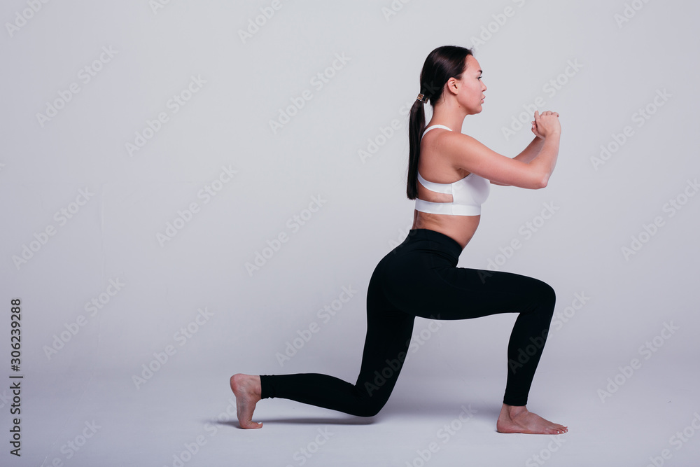 girl shows poses for yoga and warm-up in black leggings and a white T-shirt barefoot on a white background