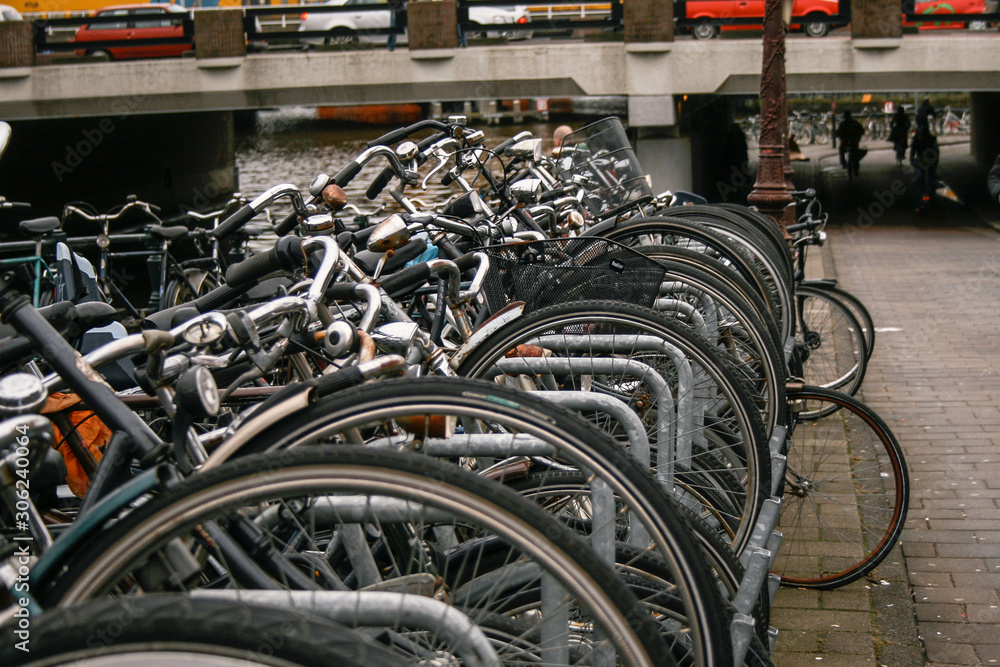 Bicycles parked in line with an Amsterdam canal next to it and the train passing in the background over a bridge Bicycles parked in line with an Amsterdam canal next to it and the train passing in the background over a bridge