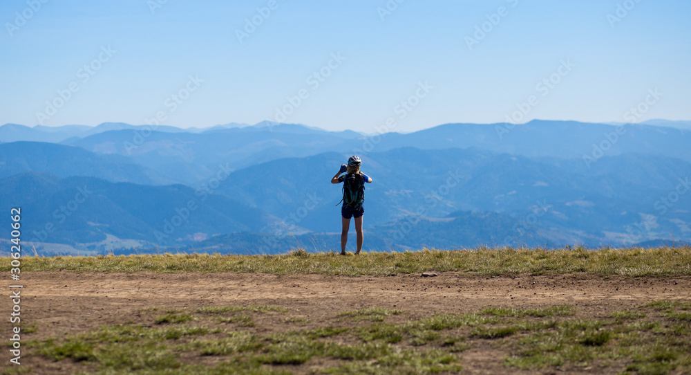 Young sport woman ride on bike by top of mountains and make picture on phone of beautiful view