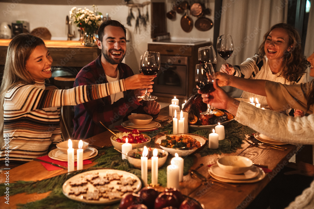 Photo of people drinking wine and smiling while having Christmas dinner