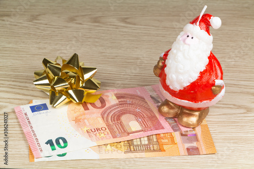 Euro banknotes, golden bow and Santa Claus figurine