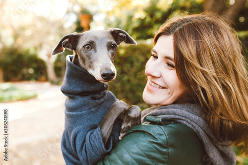 Fotografie Photo of joyful woman with dog, feels fun, carries her lovely Italian Greyhound
