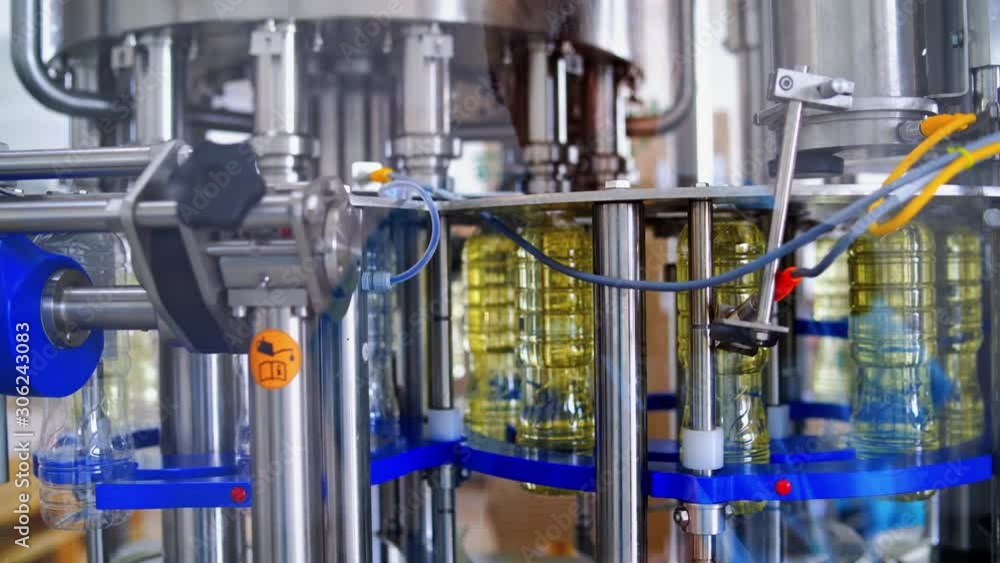 Sunflower oil production plant. Bottles filled with sunflower oil through special tubes Sunflower oil production plant. Bottles filled with sunflower oil through special tubes