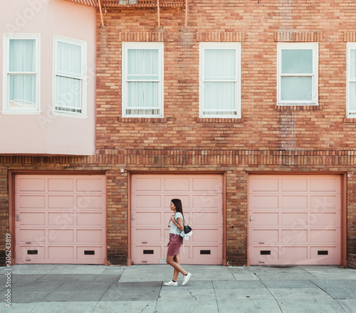 girl walking through the city next to a pink building