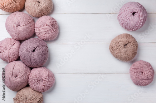 Woolen skeins of thread on white boards. ball of thread from Italian Angora. A knitting project is underway. A piece of knitting with a ball of yarn and knitting needles.