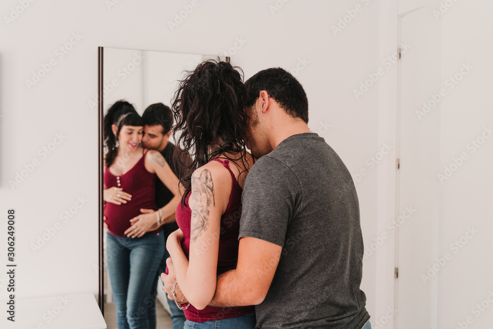 young couple at home hugging. Happy Pregnant woman. Reflection on mirror young couple at home hugging. Happy Pregnant woman. Reflection on mirror