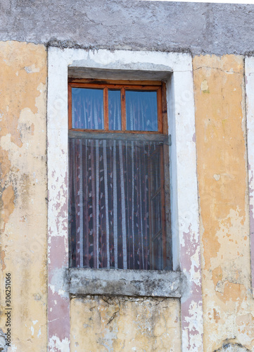 Window with Sheer Curtains in a Building with Chipped Gold Paint over Stucco