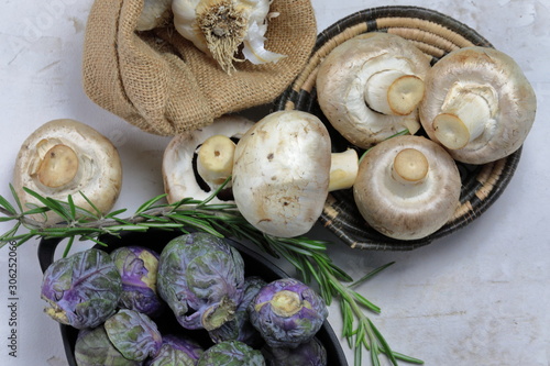 Top down view of purple Brussels Sprouts and white Button Mushrooms with a sprig of Rosemary