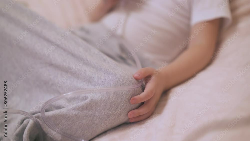 little child undergoes procedure with inhaler lying in soft bed with grey blanket in room close focus on hand little child undergoes procedure with inhaler lying in soft bed with grey blanket in room close focus on hand
