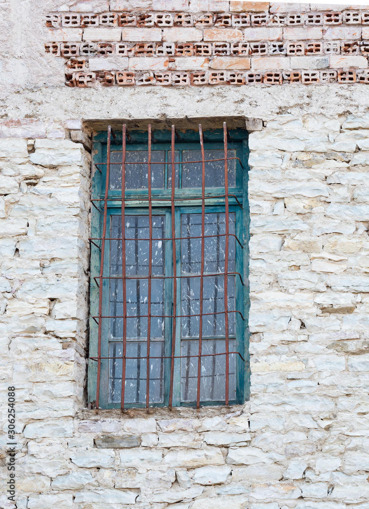 Window with Dirty Glass and Worn Turquoise Trim in a White Stone Wall