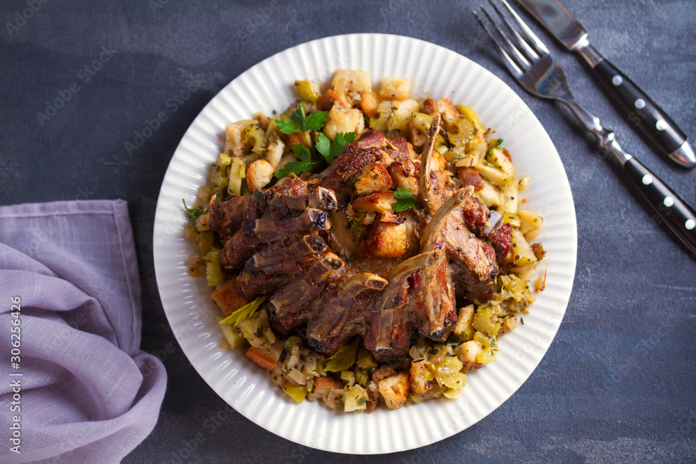 Crown roast of pork stuffed with apples and bread crumbs and celery sticks on white plate Crown roast of pork stuffed with apples and bread crumbs and celery sticks on white plate