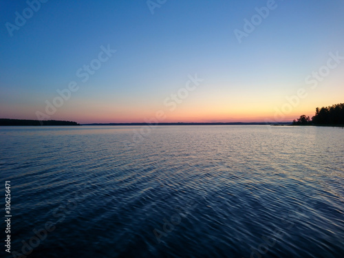 Sunset sky on lake in finland calm coast water blue vibrant sky background
